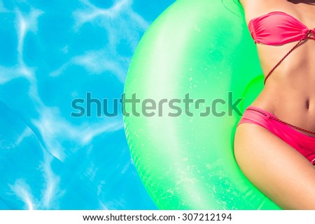 Cropped image of a young woman lying on air mattress in swimming pool