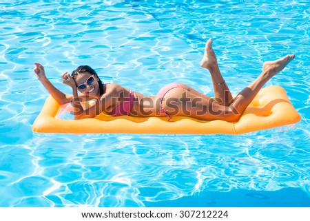 Portraito f a happy woman lying on air mattress in the swimming pool outdoors