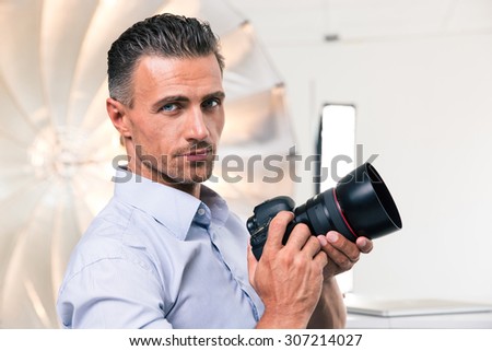 Portrait of a handsome photographer holding camera and looking at camera