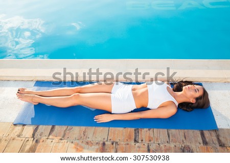 Portrait of a young woman lying on yoga mat outdoors