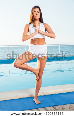 Portrait of a beautiful girl standing in yoga pose on one leg outdoors