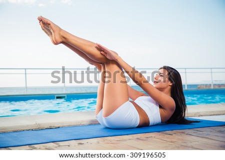 Portrait of a charming woman stretching on yoga mat outdoors in the morning