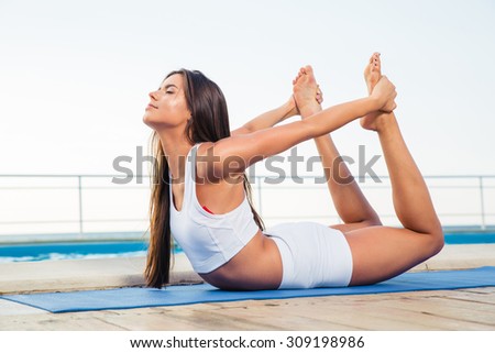 Portrait of a young girl doing stretching exercises outdoors in the morning