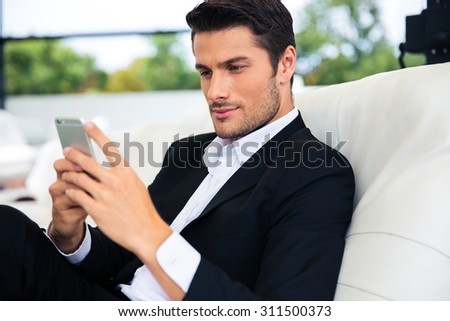 Confident businessman using smartphone in restaurant