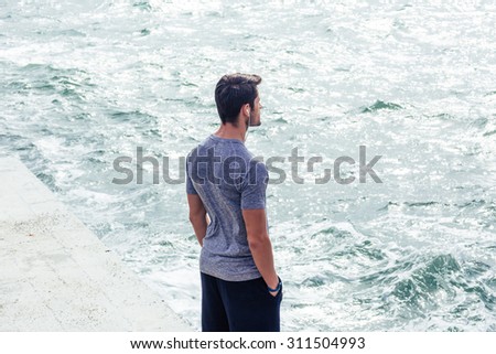 Portrait of a young man in sports wear standing near sea