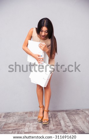 Businesswoman dropping folders on the floor over gray background