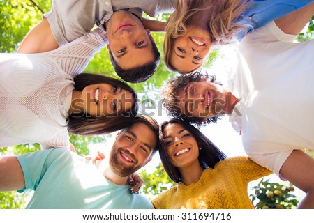 Group of friends hugging together at the park in a circle