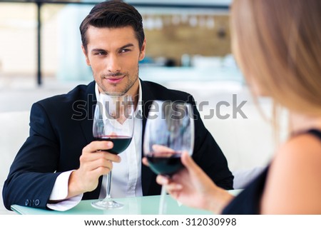 Handsome formal man drinking red wine with his girlfriend in restaurant