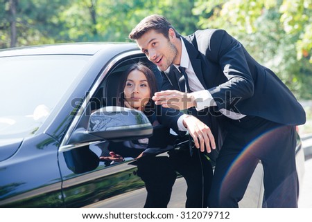Man points the direction at the road to woman in car