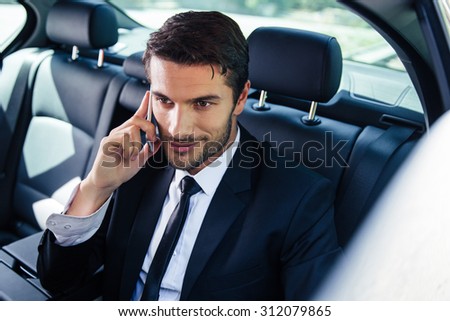 Happy businessman talking on the phone in car