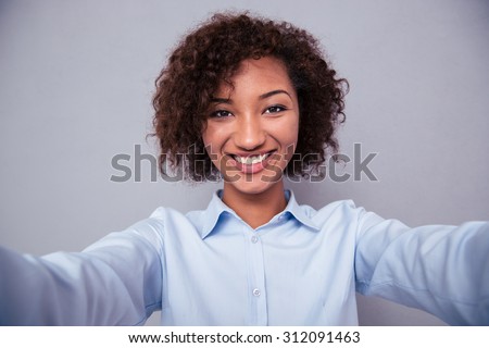 Portrait of a happy afro american woman making selfie photo on gray background
