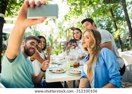Portrait of a friends making selfie photo on smartphone in outdoor restaurant