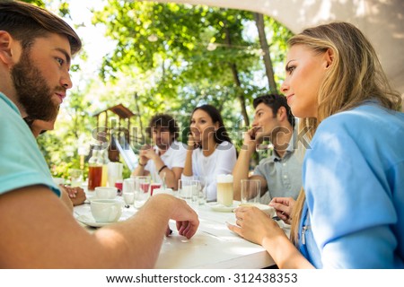 Group of a happy friends sitting at the table in outdoor restaurant
