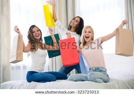 Portrait of a cheerful three girlfriends with many shopping bags at home