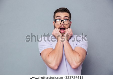 Portrait of a scared man looking at camera over gray background