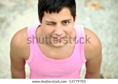 Handsome man in pink t-shirt winking outdoors
