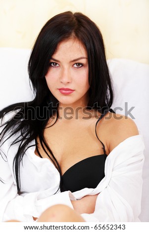 Young beautiful woman sitting on the sofa with bra exposed