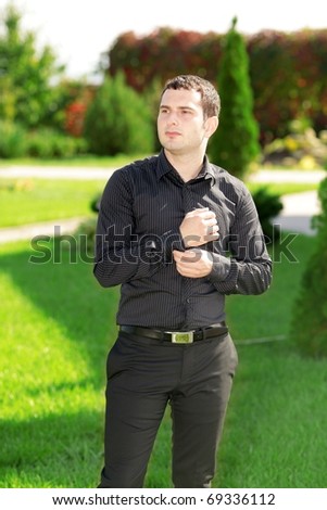 Portrait of young attractive business man standing in the yard in front of his house. Sunny day.