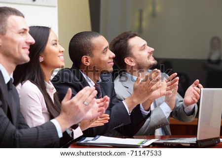 Multi ethnic business group greets somebody with clapping and smiling. Focus on african-american man