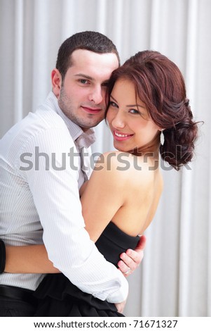 Photo of a young happy couple hugging at party