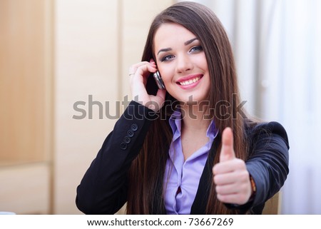 Happy successful businesswoman with cell phone and thumbs up gesture