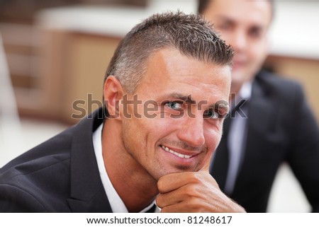 Serious mature businessman in business meeting at office, looking at camera