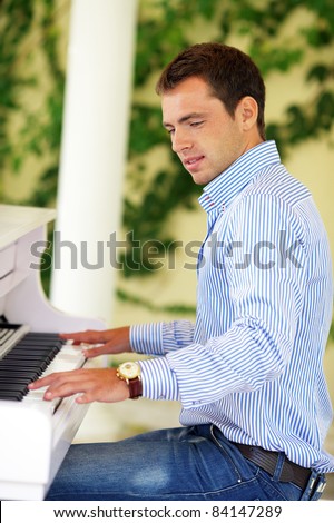Handsome young men playing white luxury piano in the garden
