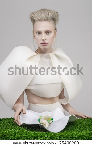 Pale blonde woman in white outfit eating health food