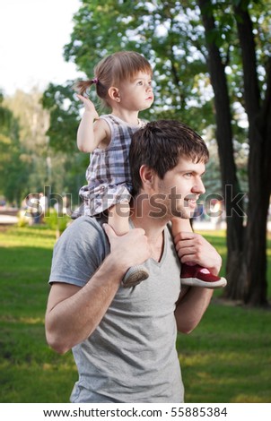 Little daughter riding father on shoulders