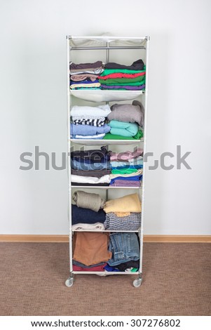 clothes nicely arranged on a shelf. Tidy wardrobe with colorful clothes and accessories against the wall