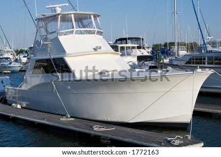 An unmarked, bright white yacht sits tied to the dock.  Perfect for someone to add their own text or graphics in the whitespace.