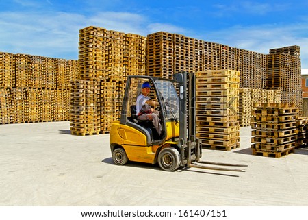 Forklift operator in pallet warehouse on the open