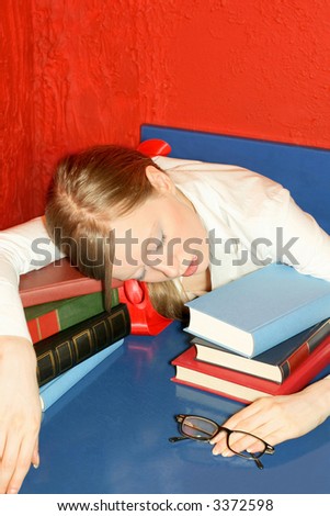 Tired blonde girl sleep over log of books
