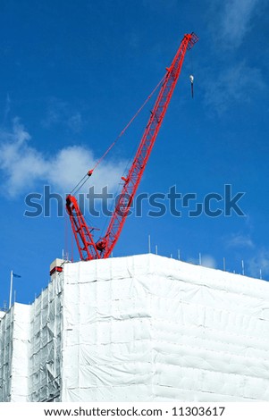 Big red construction crane on top of building