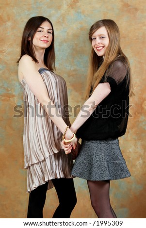 Two beautiful young fashion women holding hands