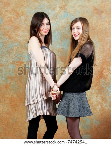 Two beautiful young fashion women holding hands