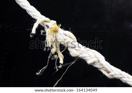 Frayed rope about to break. On black background
