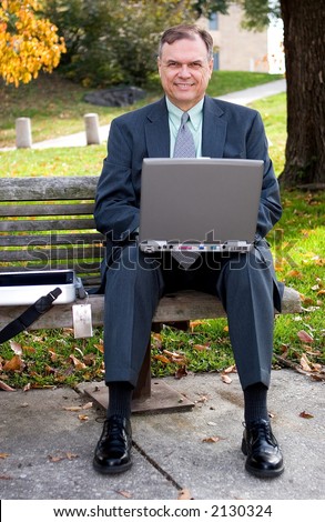 Businessman using laptop on a park bench