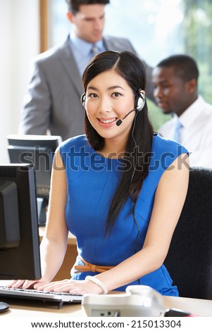 Businesswoman Wearing Headset Working In Busy Office