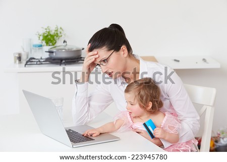 Stressed Mother With Child Using Laptop At Home