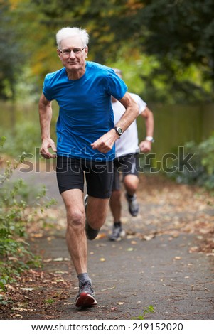 Two Mature Male Joggers Running Along Path
