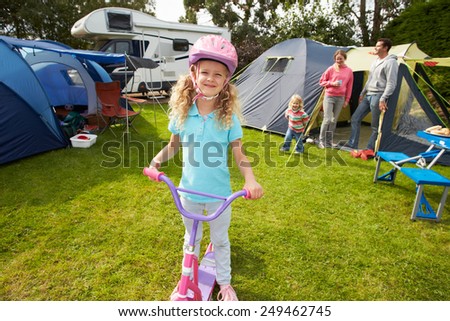 Girl Riding Scooter Whilst On Family Camping Holiday