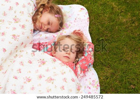 Two Girls Lying Under Blanket On Camping Holiday