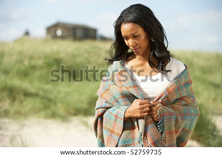 Thoughtful Young Woman Standing On Beach Wrapped In Blanket
