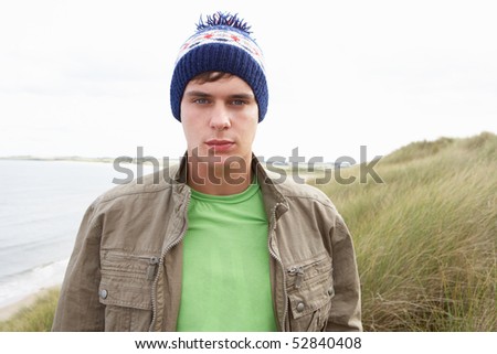 Teenage Boy Standing In Sand Dunes Wearing Woolly Hat