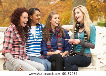 Group Of Four Teenage Girls Sitting On Bench In Autumn Park Stock Photo ...