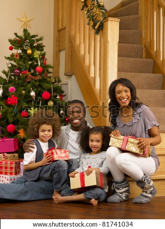 Young African American family with Christmas tree and gifts
