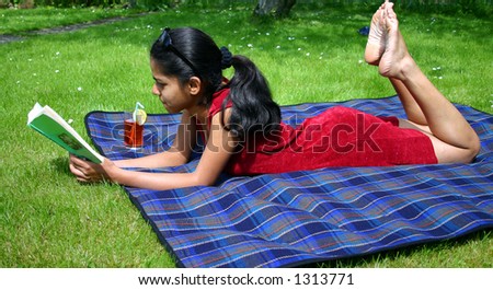 Indian woman relaxing on the lawn with a good book