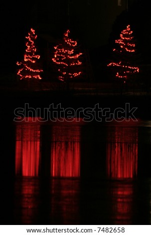 Red christmas trees reflecting off of icy lake