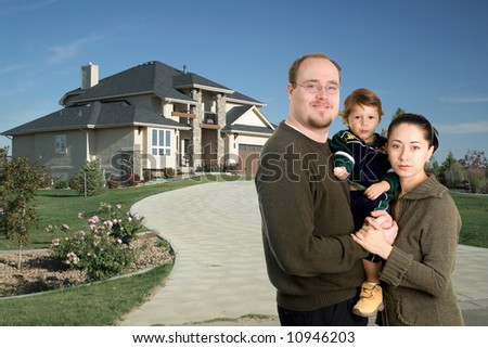 Young family standing together in front of luxury home